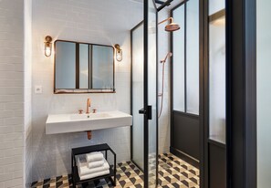 A modern bathroom with a white sink, a large mirror, and a glass-enclosed shower.