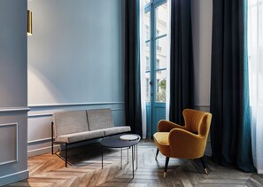 A modern room with a blue wall, a sofa, a round table, and a yellow armchair.