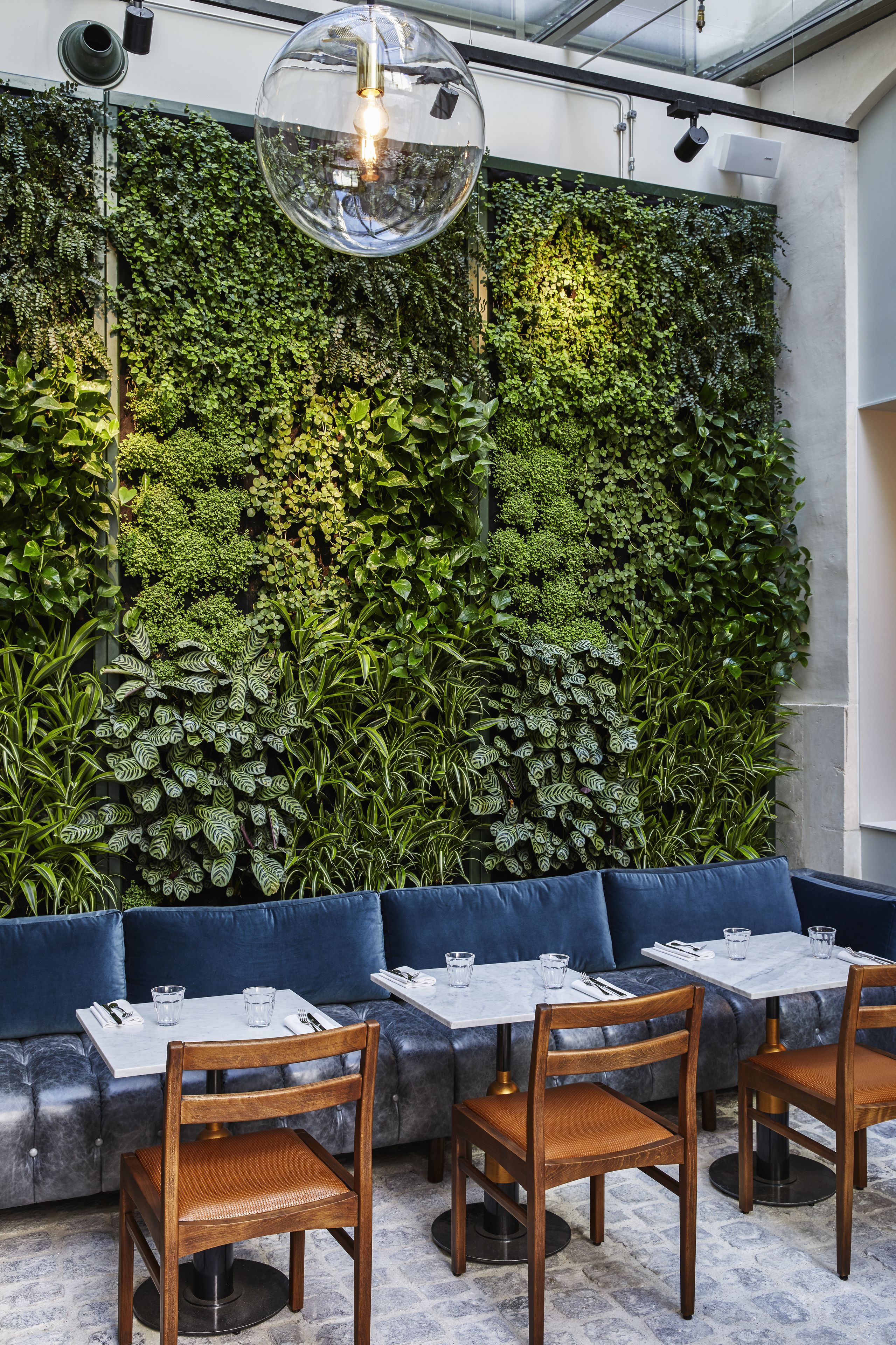 A restaurant interior with a green wall, blue seating, and wooden chairs.