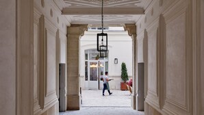 A corridor with a stone floor, white walls, and a hanging lantern. - The Hoxton, Paris (Paris)