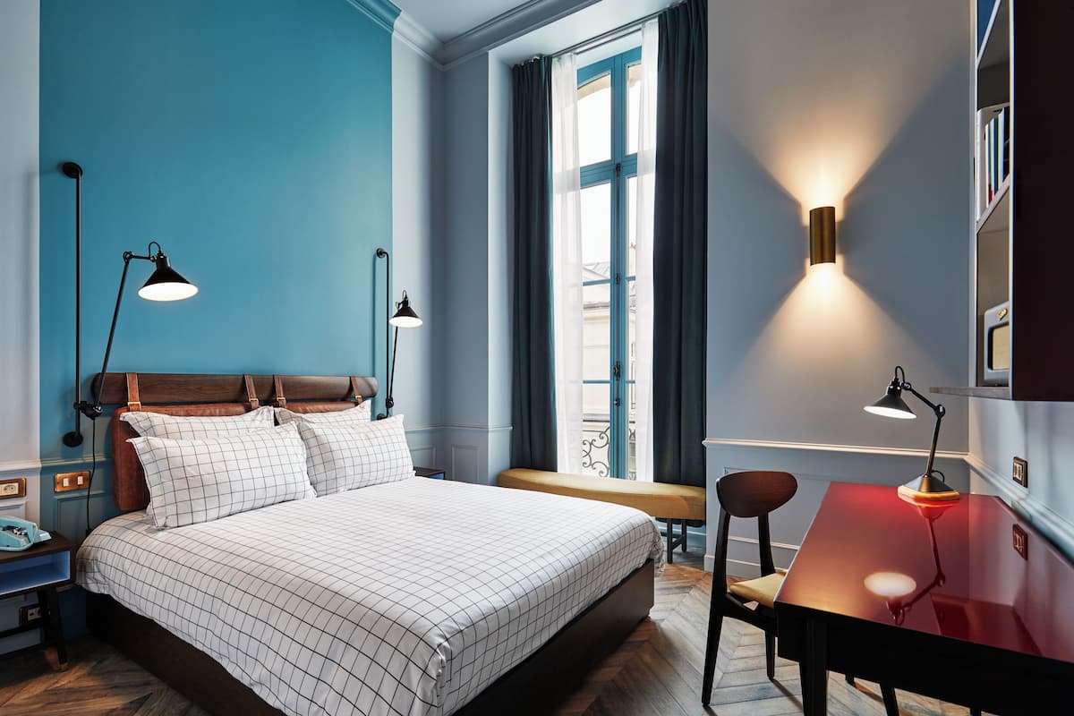 Een slaapkamer met een bed, nachtkastjes, een bureau en een stoel.