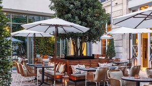 An outdoor seating area with tables and chairs, surrounded by large umbrellas, and a central seating area with a tree. - The Hoxton, Paris (Paris)