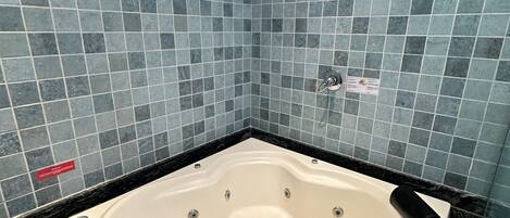 Un baño con una bañera independiente, paredes de azulejos y una encimera de mármol negro.