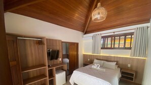 Un dormitorio con una cama grande, un armario de madera y una televisión.