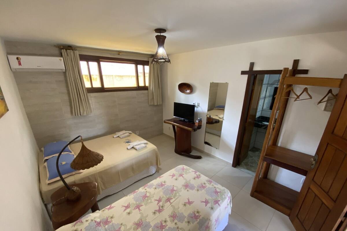 A bedroom with a bed, a desk, a TV, a mirror, and a wardrobe.