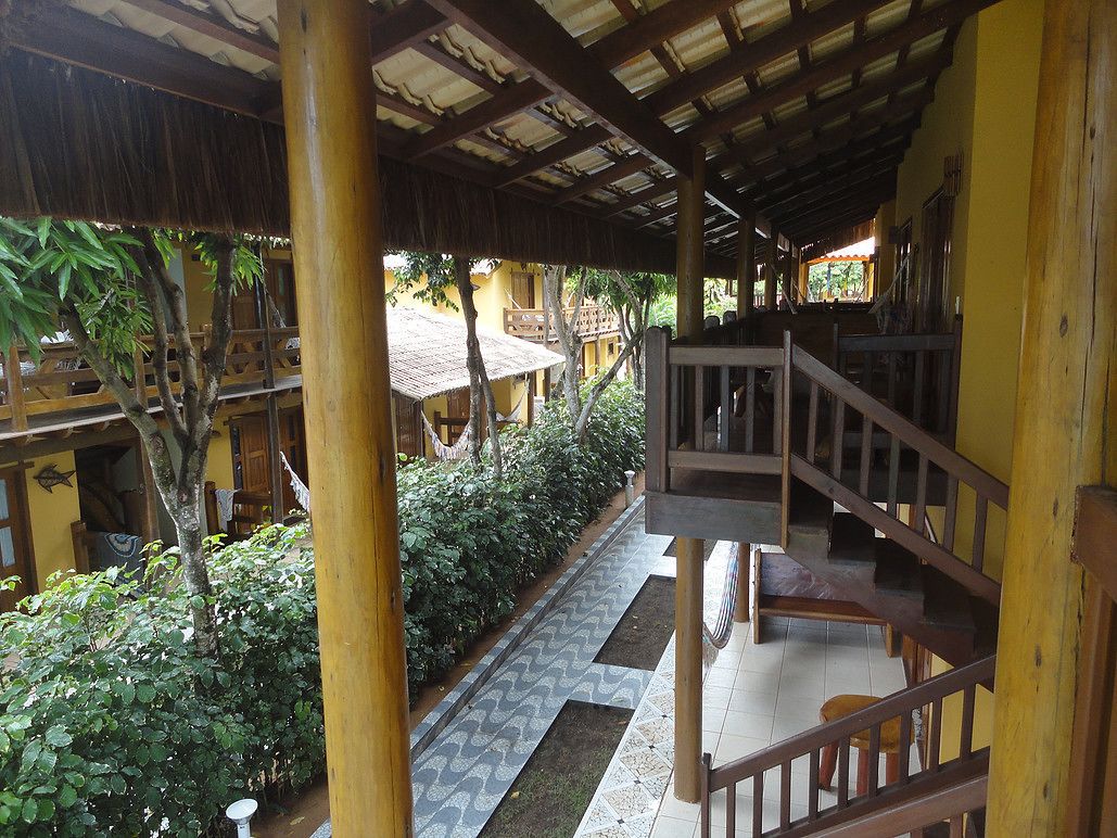 Un espacio al aire libre cubierto, con una escalera de madera y un camino empedrado.