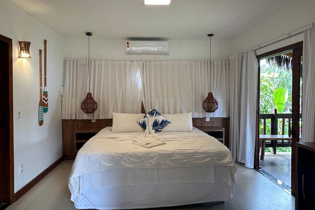 A spacious bedroom with a large bed, a ceiling fan, and a view of the outdoors.
