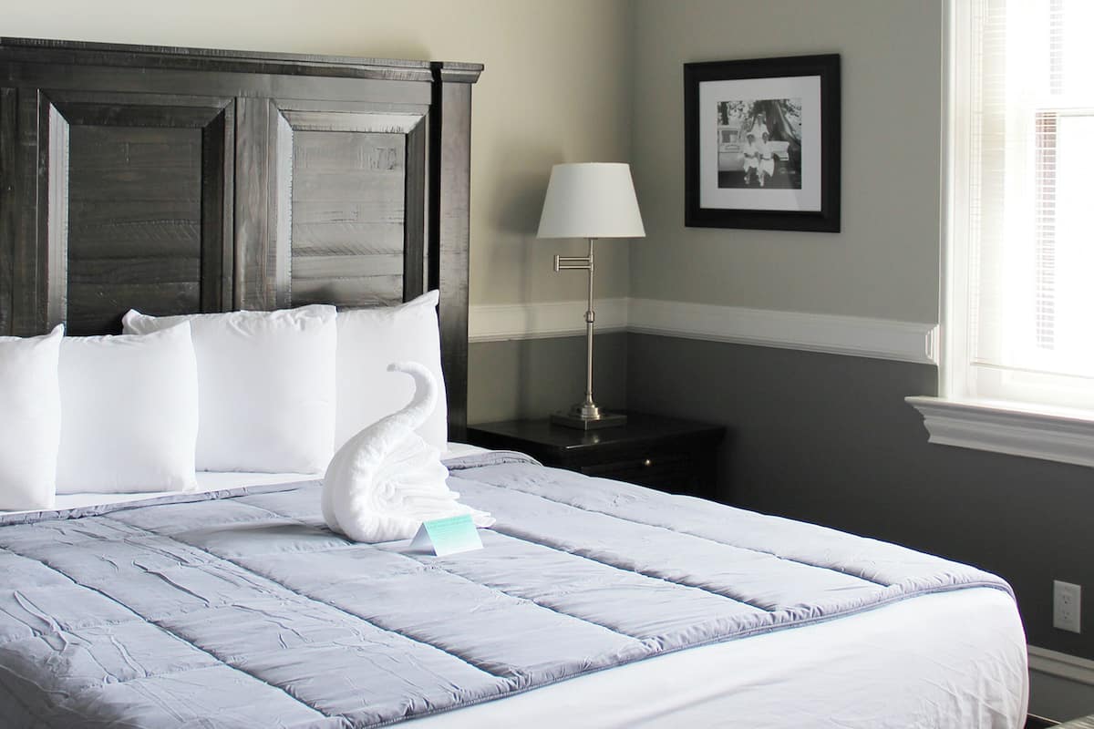 Een keurig opgemaakt bed met witte lakens en een zwaan-vormig kussen.
