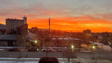 A parking lot with several cars, a building with a sign, and a sunset in the background.