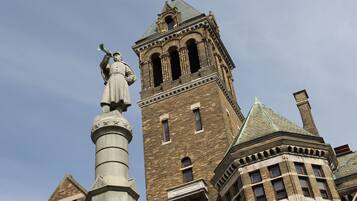 Un edificio histórico con una torre destacada y una estatua sobre un pilar.
