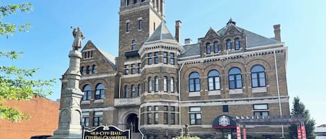 A historic building with a prominent tower, a fountain, and a sign indicating it is the Old City Hall Grand Hotel.