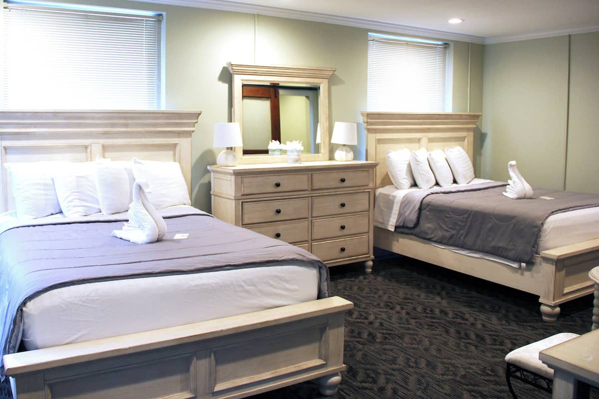 Een hotelkamer met twee bedden, een dressoir, een spiegel en een stoel.