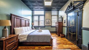A bedroom with a large bed, wooden dresser, and a wardrobe with a lock.
