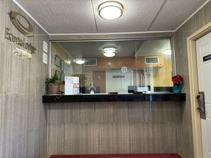 A reception area with a wooden wall, a reception desk, a clock, and a sign indicating 'Employees Only'. - Econo Lodge Waite Park - St. Cloud (Waite Park)
