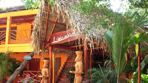 A building with a thatched roof entrance, a staircase, and two statues. - Hotel Locanda Samara Beach (Sámara)