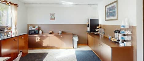 Una cocina compacta con cafetera, microondas y un refrigerador pequeño.