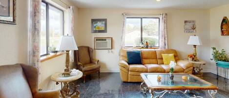 A living room with a leather sofa, a glass coffee table, and a brown armchair.