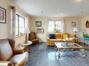 Una sala de estar con un sofá de cuero, una mesa de centro de vidrio y un sillón marrón.