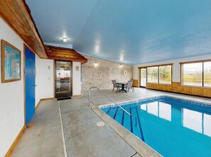 An indoor swimming pool with a clear view of the pool area, a door, and a table with chairs. - Oscoda Lakeside Hotel (Oscoda)