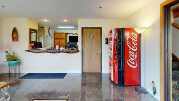 En lobby med receptionsdisk, Coca-Cola automt, et ur og en potteplante.