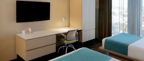 A hotel room with a bed, a desk, a chair, a TV, and a wardrobe.