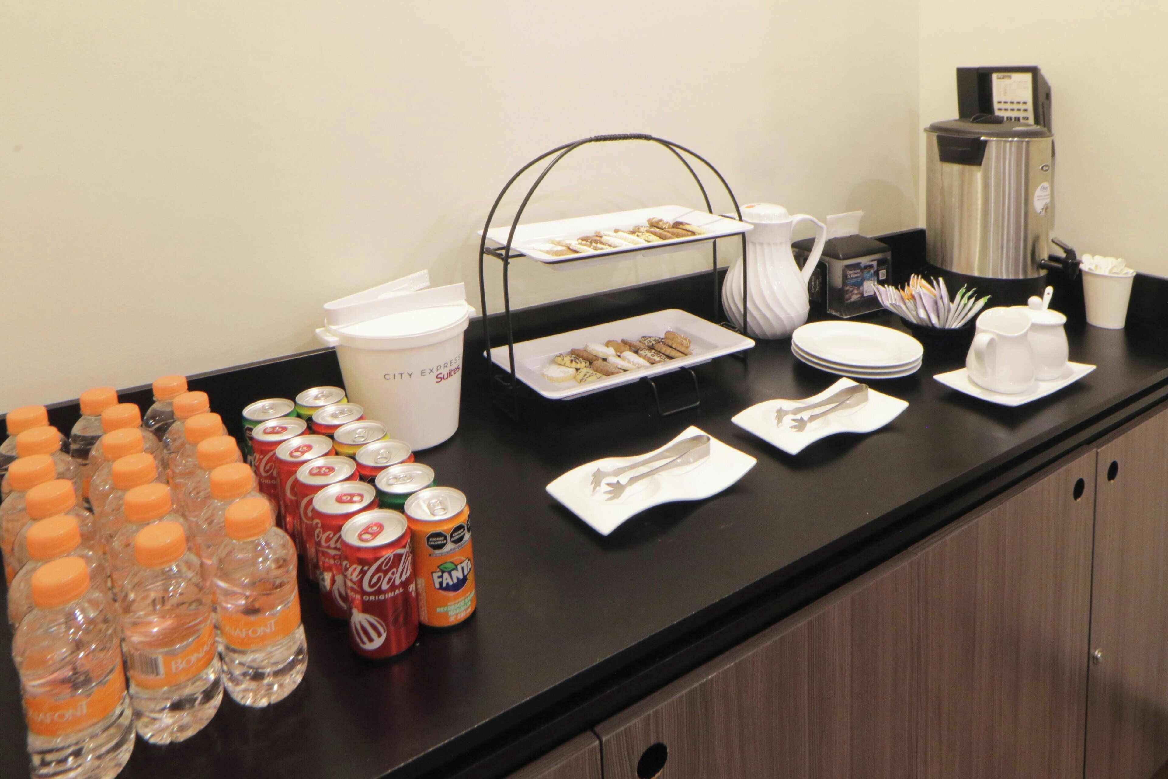 Disposición de un bufé de desayuno con bebidas, platos y cubiertos.