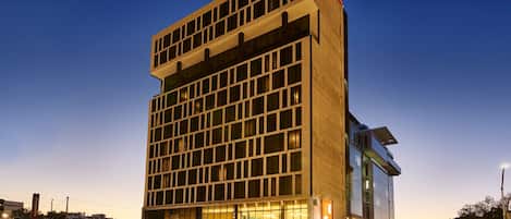 Een modern hotel met een gevel in rasterstijl, grote ramen en een opvallend bord met de tekst 'GTA Express Suites'.