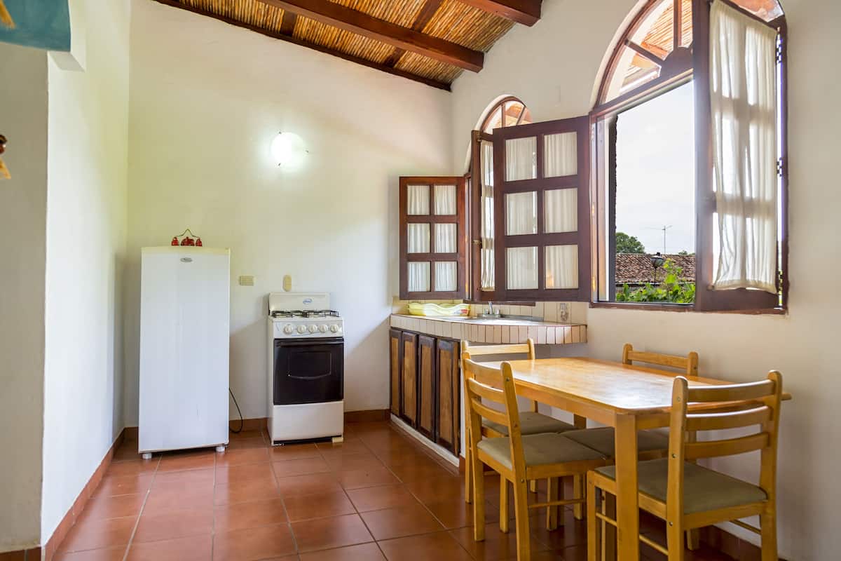 A compact kitchen with a stove, refrigerator, and wooden dining table with chairs.