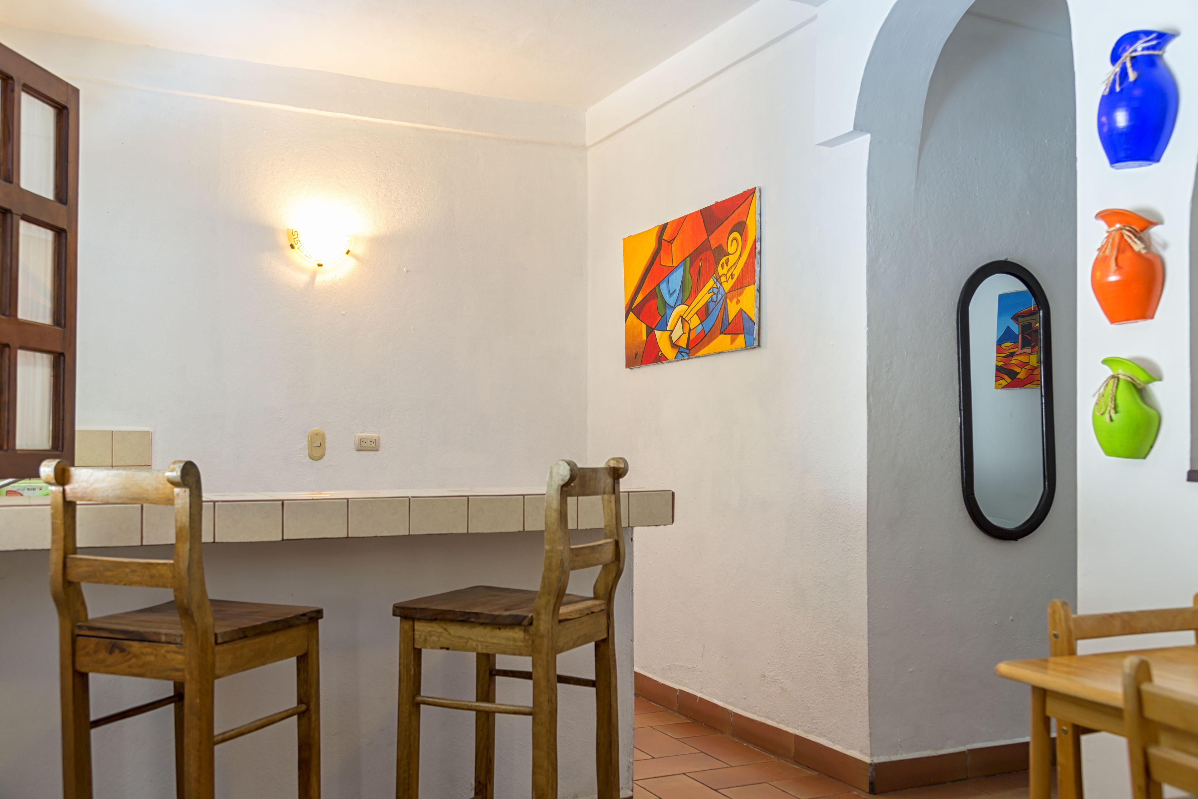 Un comedor con dos sillas de madera, una pared blanca con un cuadro y piso de baldosas.