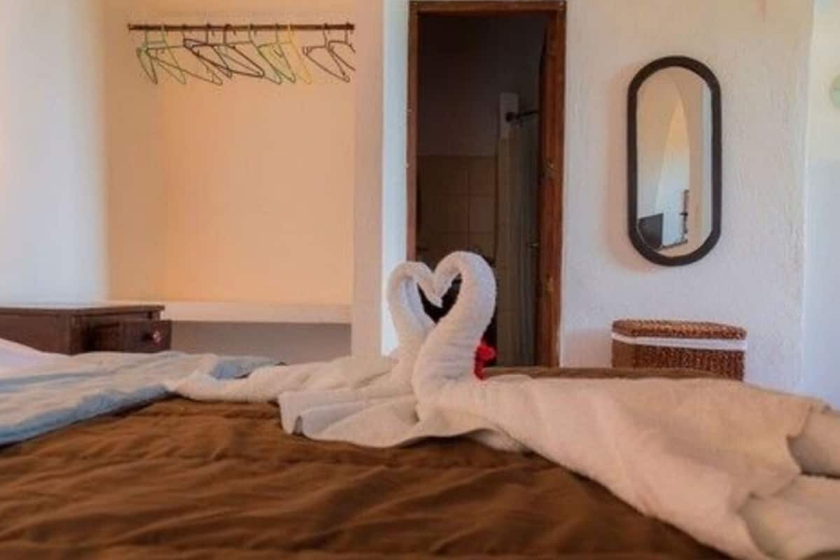A hotel room with a bed, a wooden headboard, a mirror, and a wall-mounted towel rack.