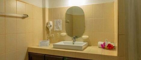 A bathroom with a sink, mirror, towel dispenser, and a hand dryer.