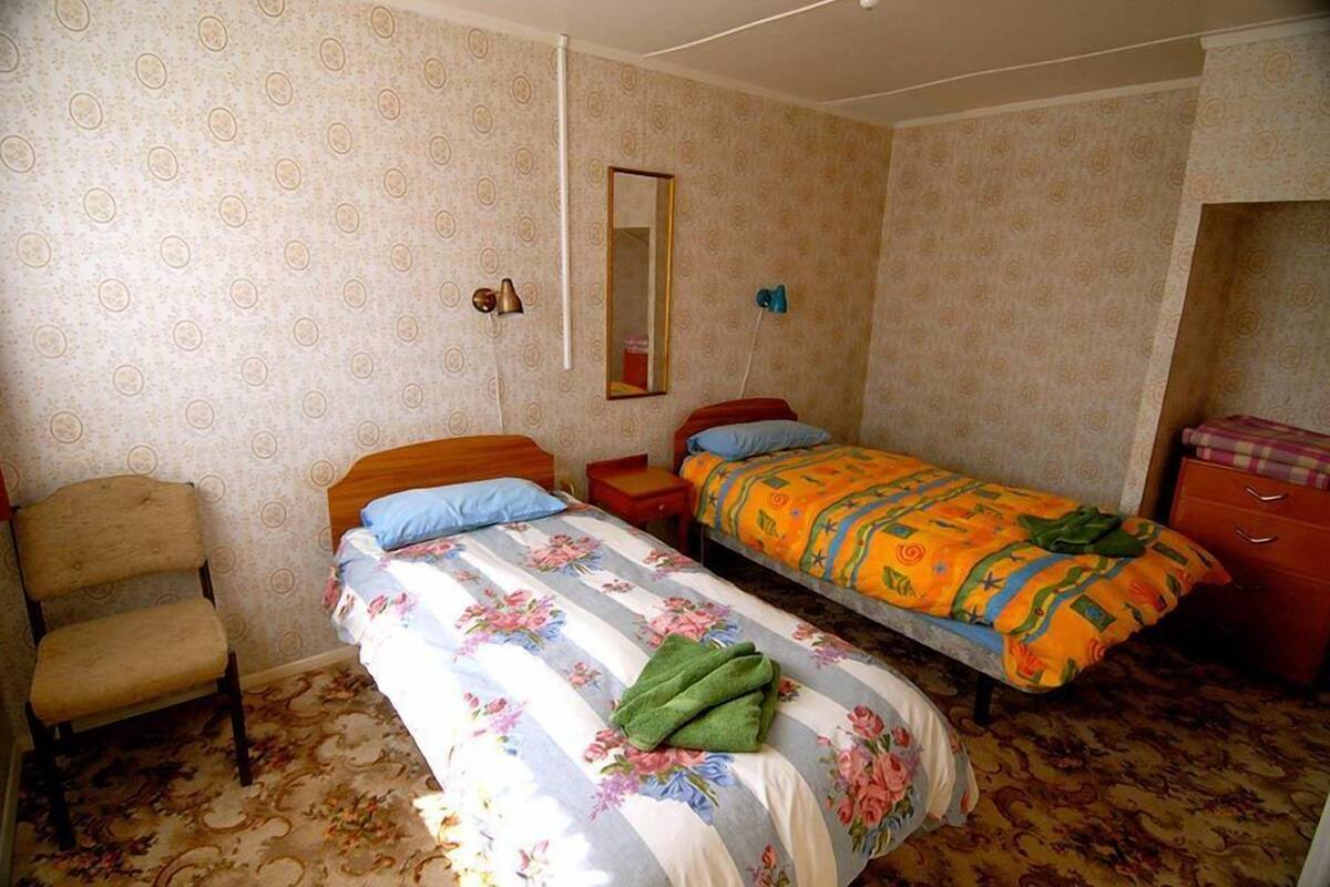 A bedroom with two beds, a chair, a mirror, and a dresser.