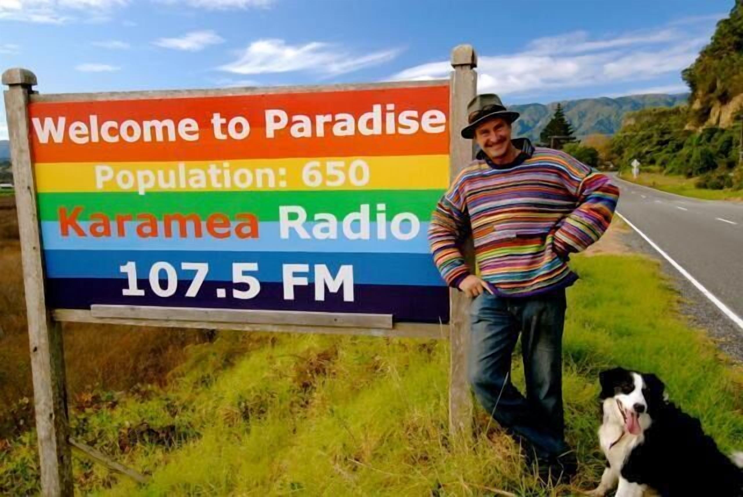 A sign welcoming visitors to Paradise with a population of 650, featuring Karamea Radio at 107.5 FM.
