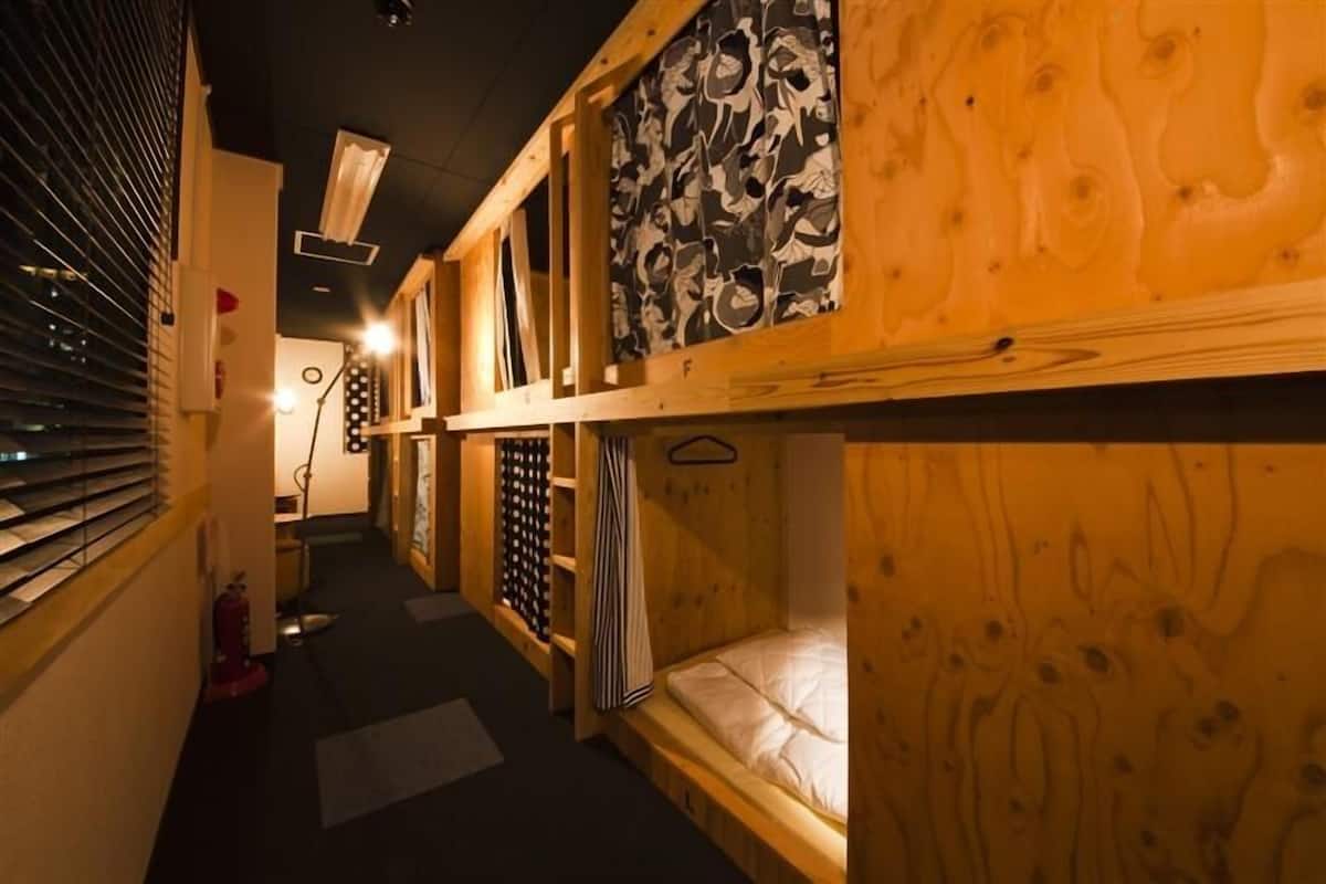 Un couloir étroit avec des lits superposés et un extincteur.