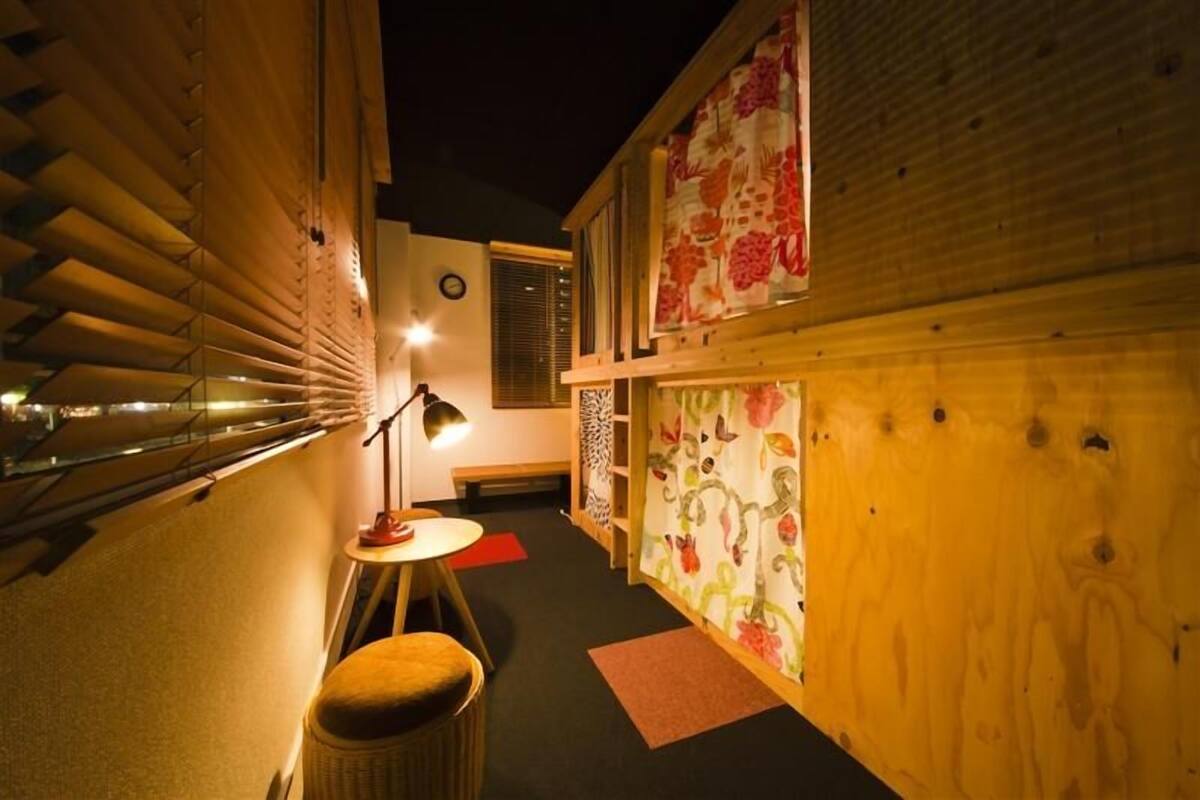 Un couloir étroit aux murs en bois, une petite table avec une lampe et une chaise.
