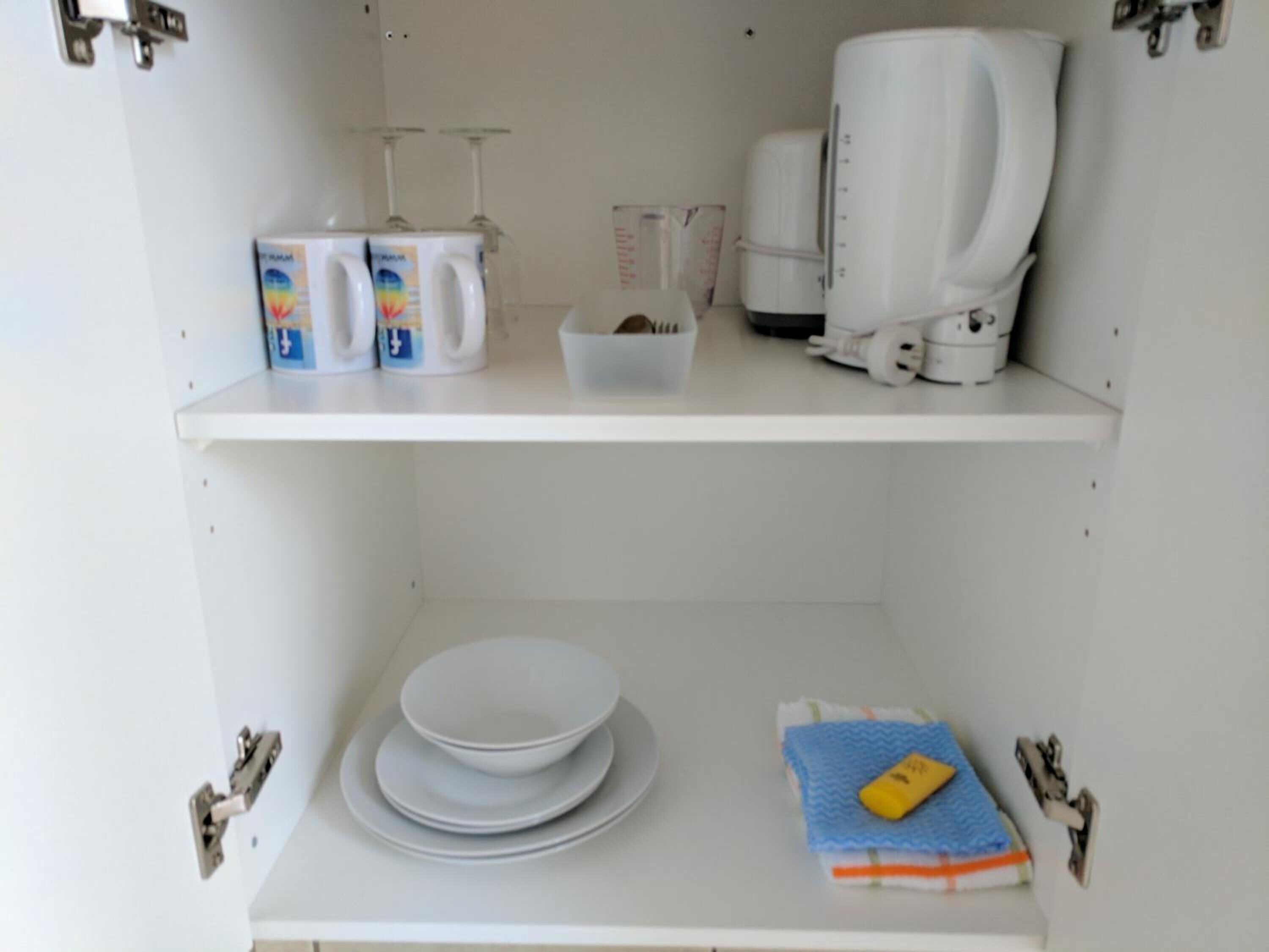 Una cocina con armarios blancos, una cafetera y un microondas en la encimera.