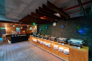 Een buffetgedeelte met verschillende stations voor eten, een klok aan de muur en een houten vloer.