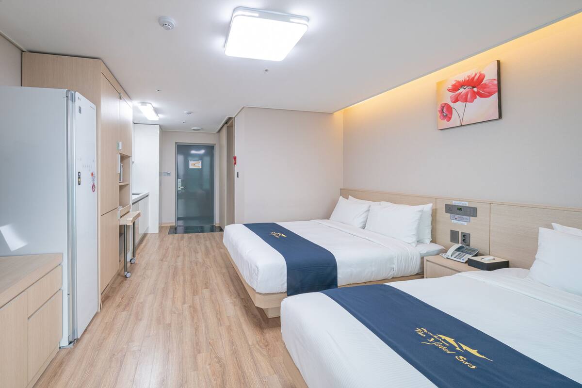 A hotel room with a bed, bedside table, TV, and a desk with a computer.
