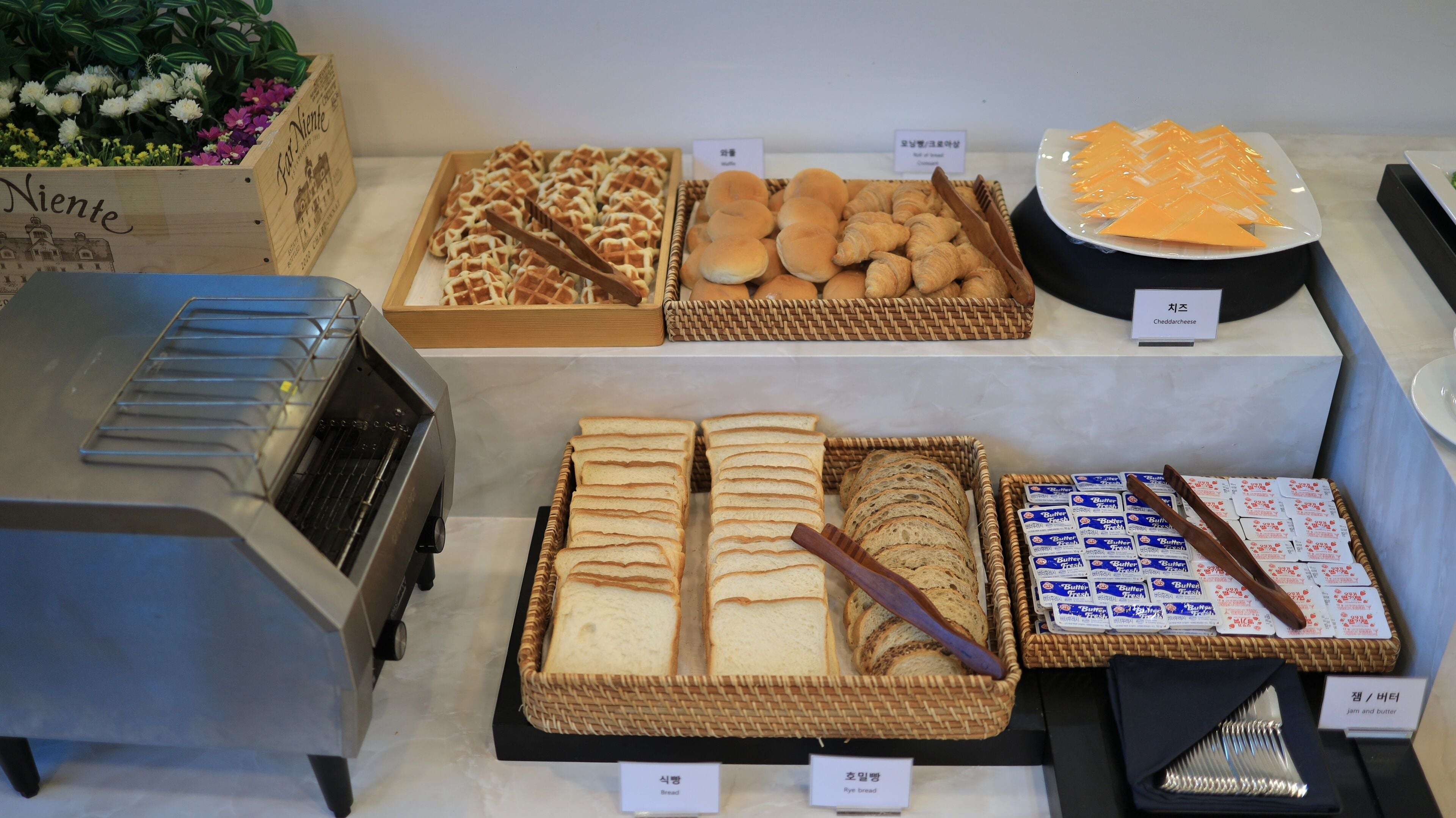 A bakery display with various breads, pastries, and cheese.