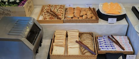A bakery display with various breads, pastries, and cheese.