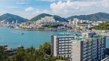 A coastal cityscape with a prominent hotel building featuring multiple floors and a rooftop terrace.