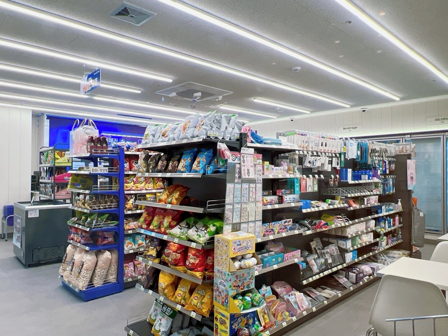 A well-lit grocery store with shelves stocked with snacks, beverages, and household items.