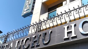Un hôtel avec une enseigne bien visible portant l’inscription « HIAUCHU HOTEL » et une clôture décorative en métal.