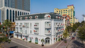 Un edificio de varios pisos con balcones, grandes ventanales y una bandera destacada.
