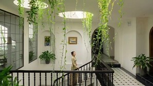 Un atrio de varios niveles con plantas colgantes, una escalera y piso de baldosas.
