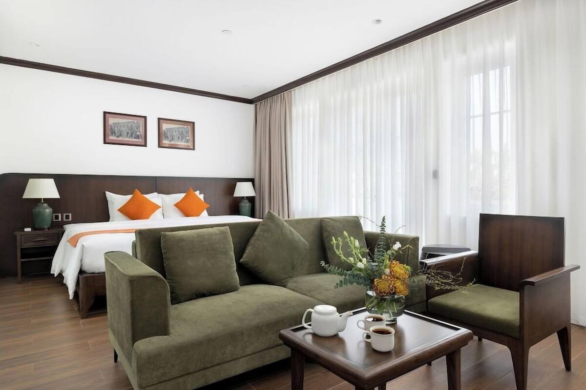 Una habitación de hotel con una cama, un sofá, una mesa de centro y un escritorio.