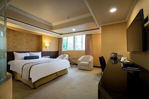A hotel room with a large bed, a desk, a chair, and a television. - Good Life Hotel Zhongshan (Taipei)