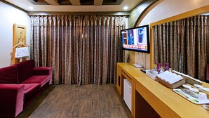 A hotel room with a red sofa, a wooden desk with toiletries, a television, and curtains. - Drama Motel (Boryeong)