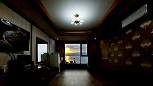 A dimly lit room with a large window, a ceiling fan, and patterned wallpaper. - Drama Motel (Boryeong)