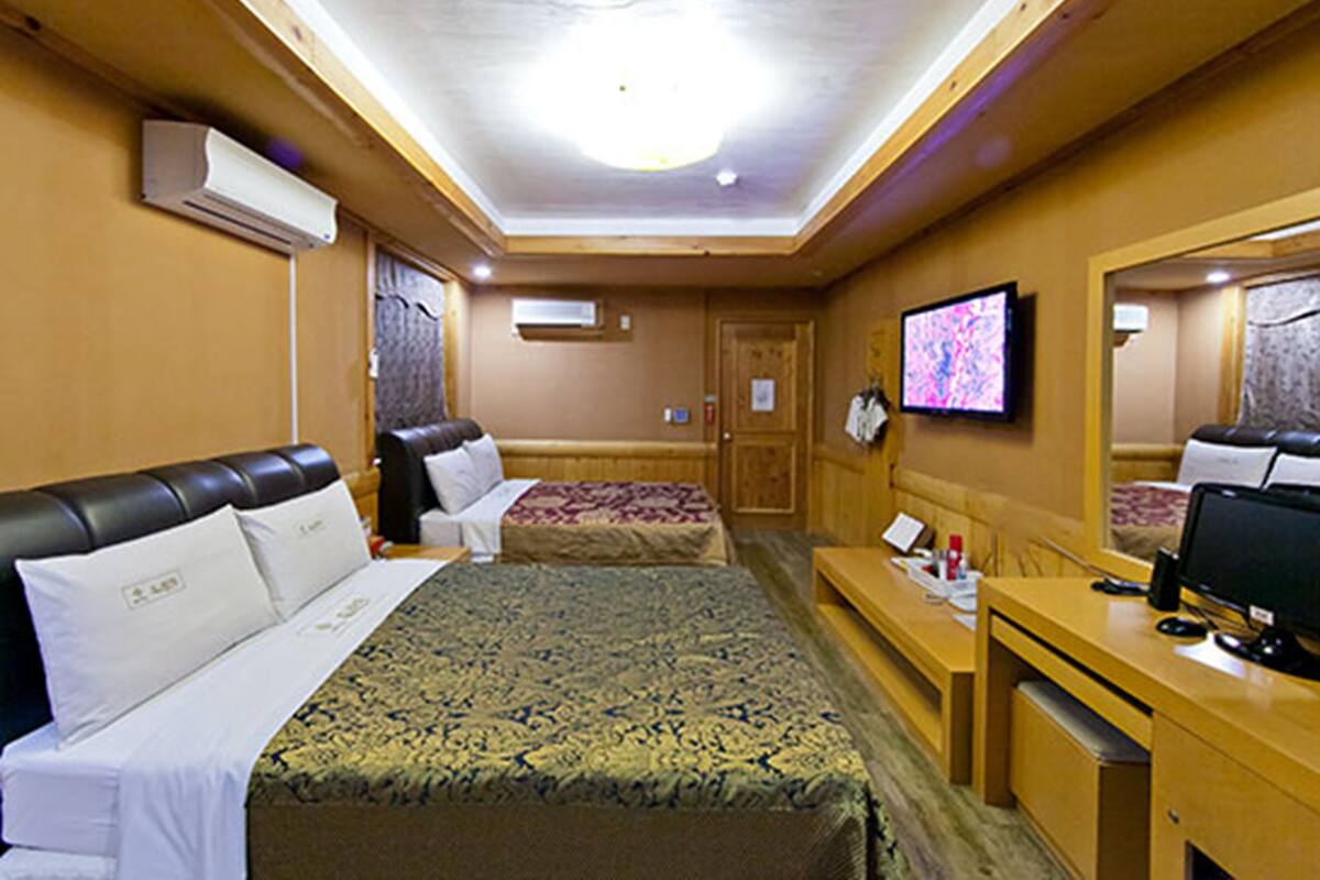 Una habitación de hotel con dos camas, un escritorio, un televisor y aire acondicionado.